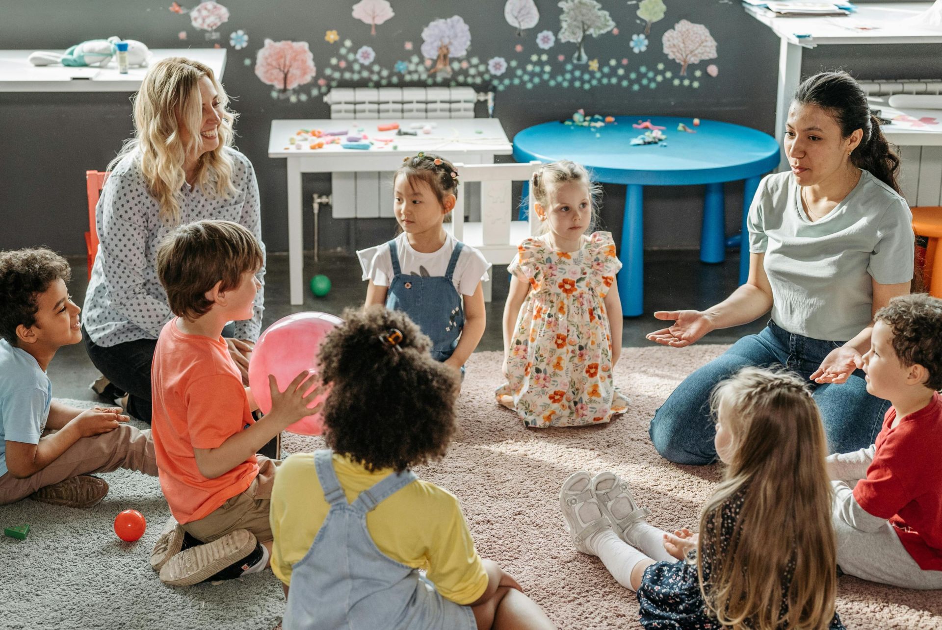 Children in circle time with teachers, engaging in a kindergarten classroom activity.