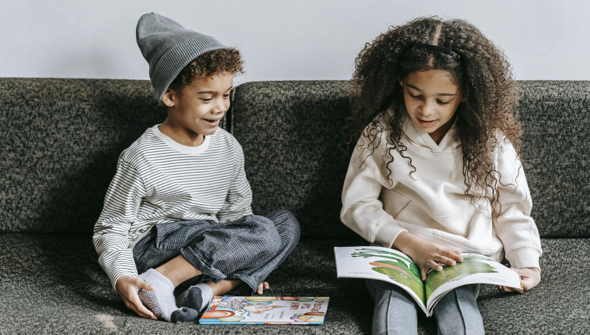 Siblings reading a picture book together indoors, fostering a love of literature.