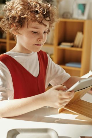 Young child using a tablet for distance learning at home, focusing intently.
