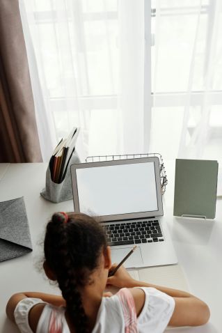 A young girl focuses on distance learning with her laptop at home.